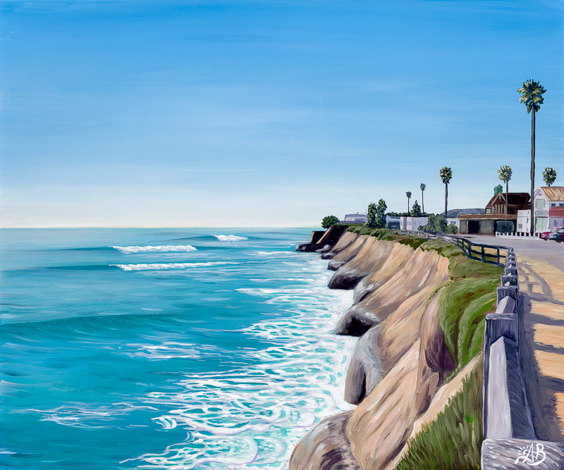 Coastal scene with cliffs, ocean waves, palm trees, and buildings along a road under a clear blue sky.