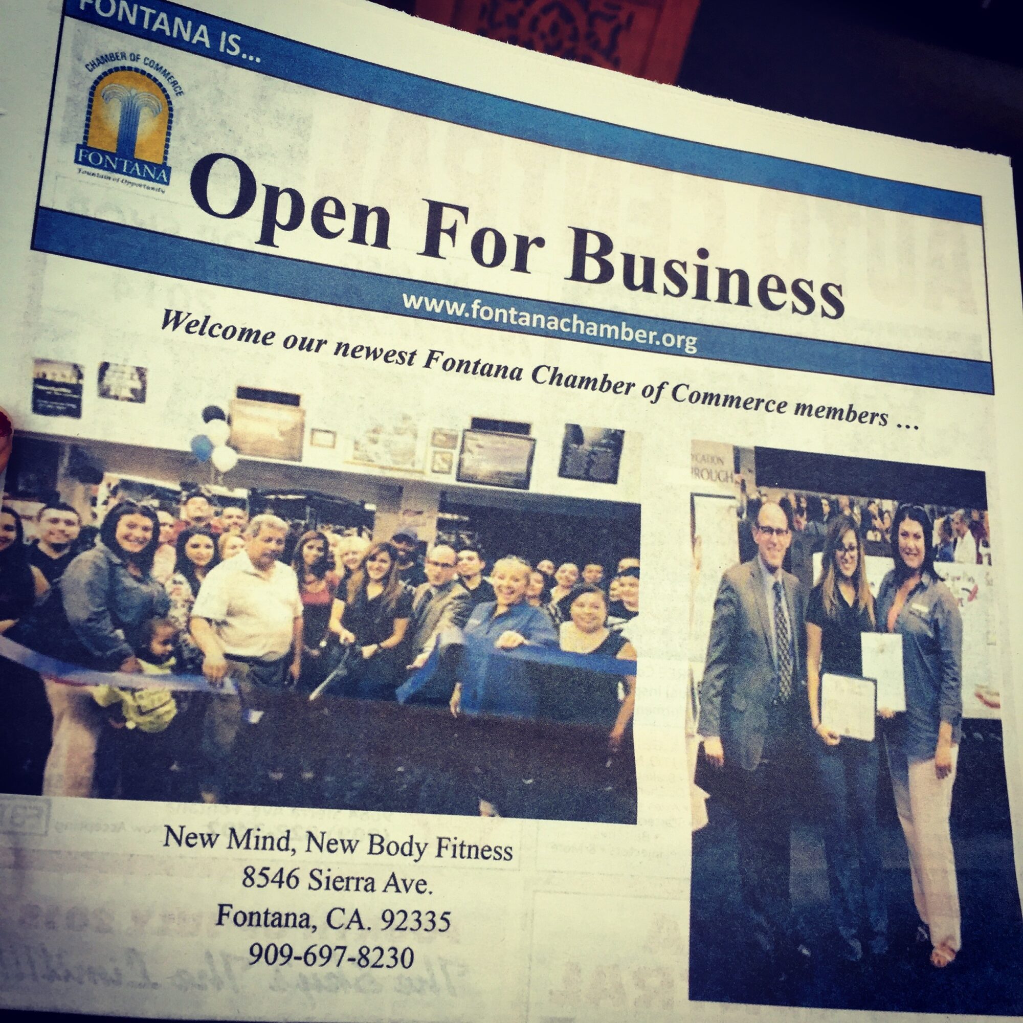 Group of people at a business event, some holding certificates, in a room with a banner reading 'Open For Business'.