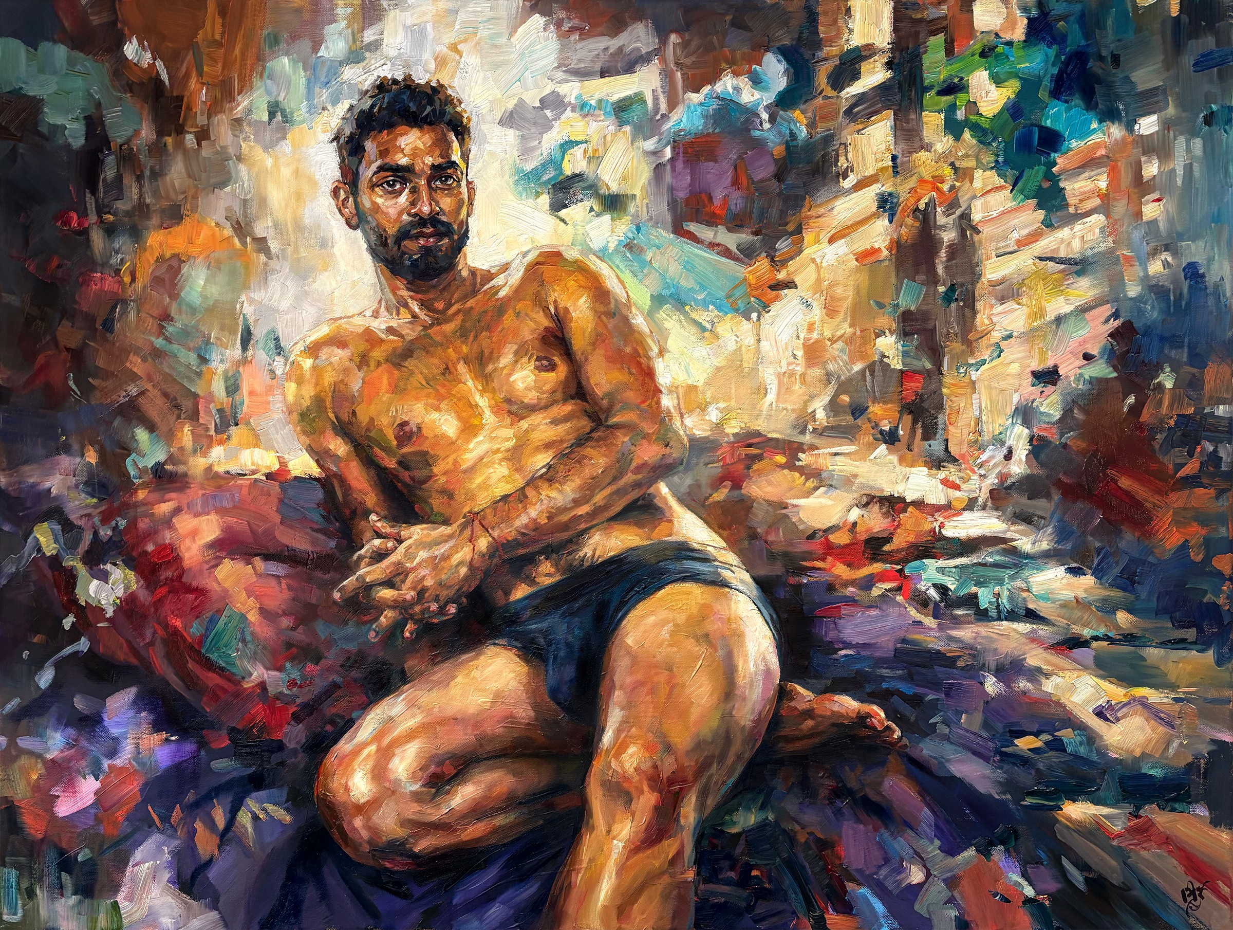 A man with a beard and glasses sitting on a colorful abstract background, wearing dark shorts, with arms crossed and legs bent.
