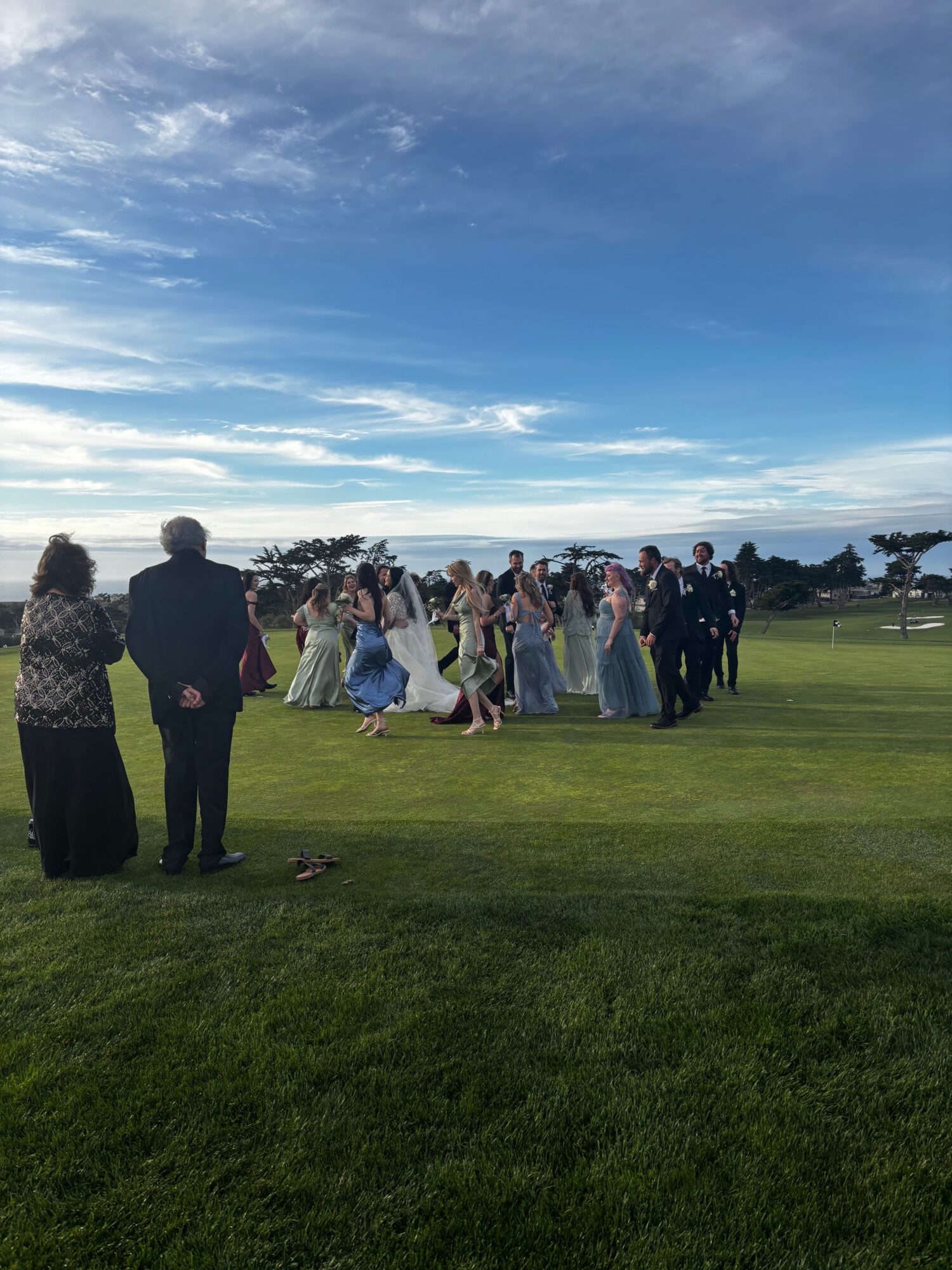 Group of people standing on a grassy field under a partly cloudy sky.