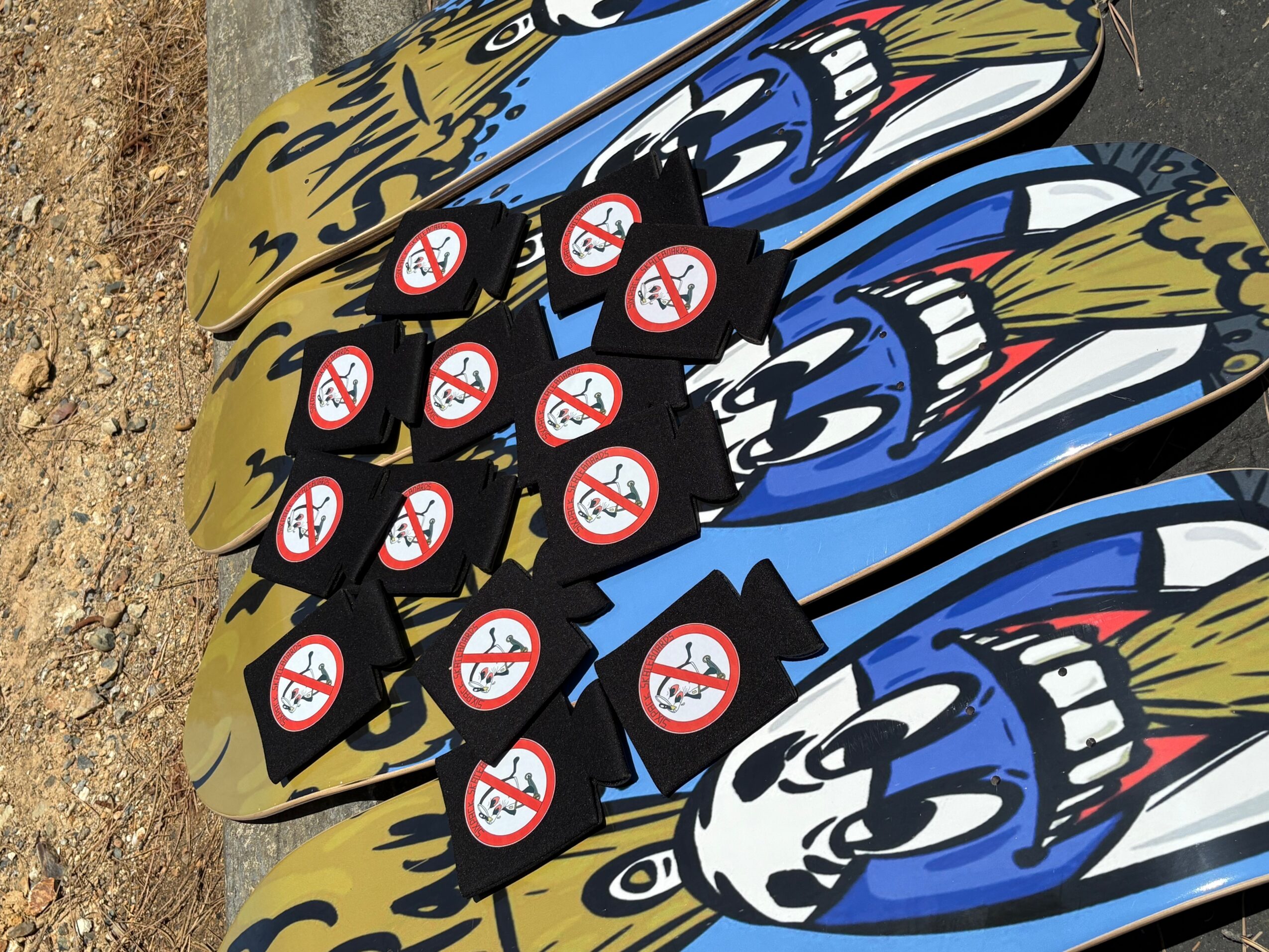 Colorful cartoon-style skateboards with no smoking signs, arranged on a surface, with a dirt background visible on the left.