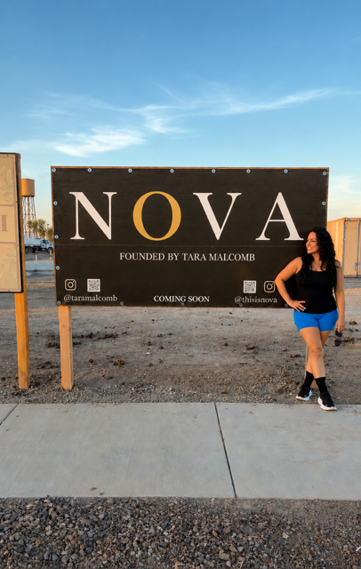 Woman standing next to a large sign that reads 'NOVA' with a blue sky background.