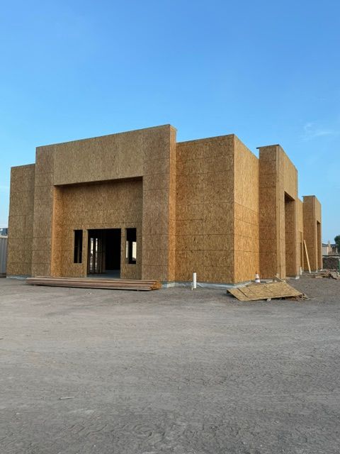 A building with a textured exterior, rectangular entrance, and a small window, under a clear blue sky.