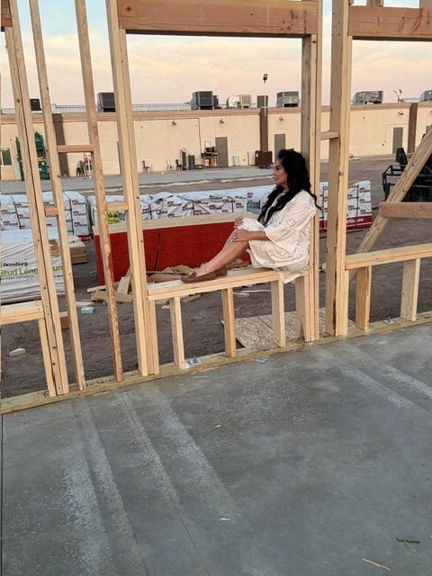 Person working on wooden frame construction in an indoor space with concrete floor and background structures.