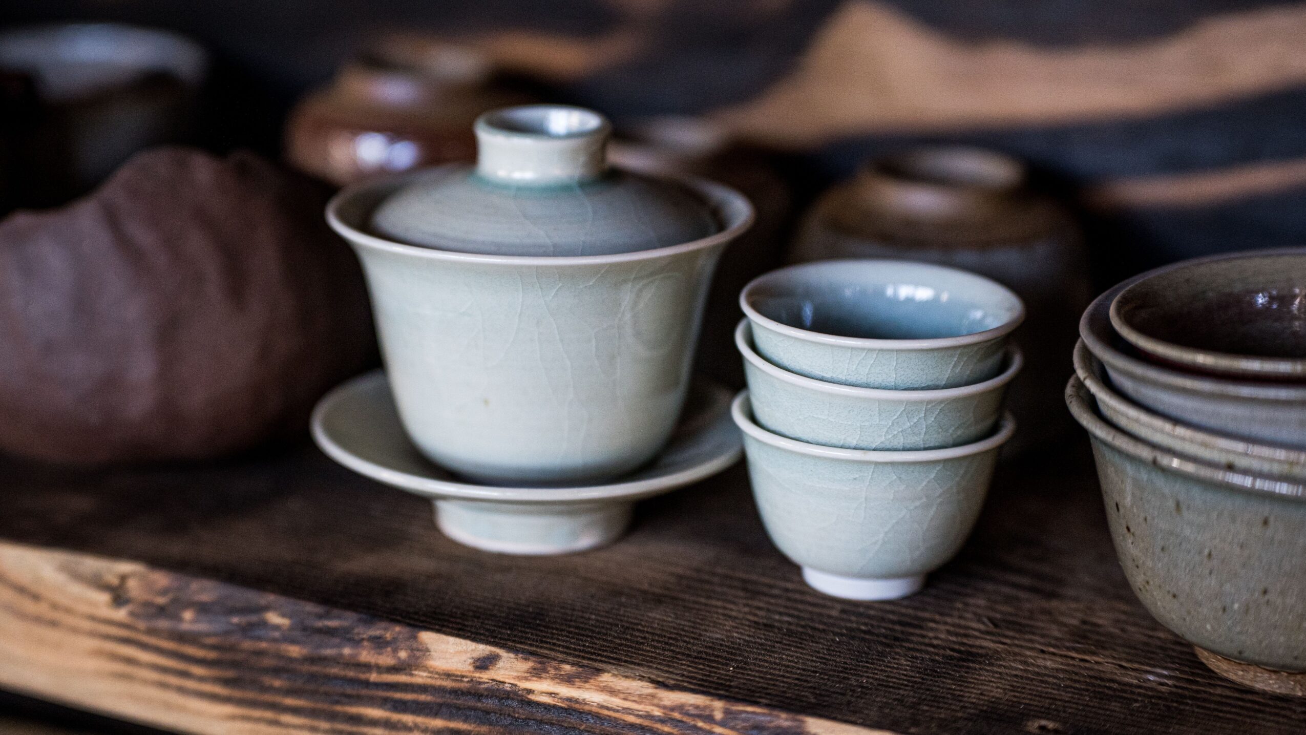 Stacked white ceramic bowls and a lid on a dark wooden surface.