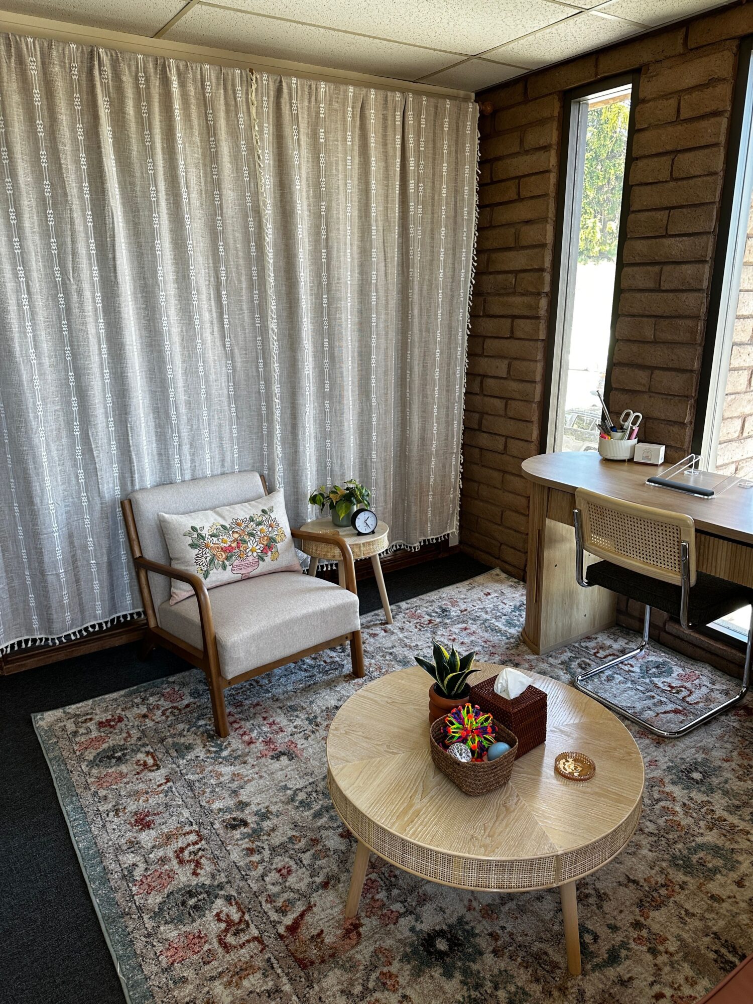 Living room with window, armchair, round coffee table, and patterned rug.