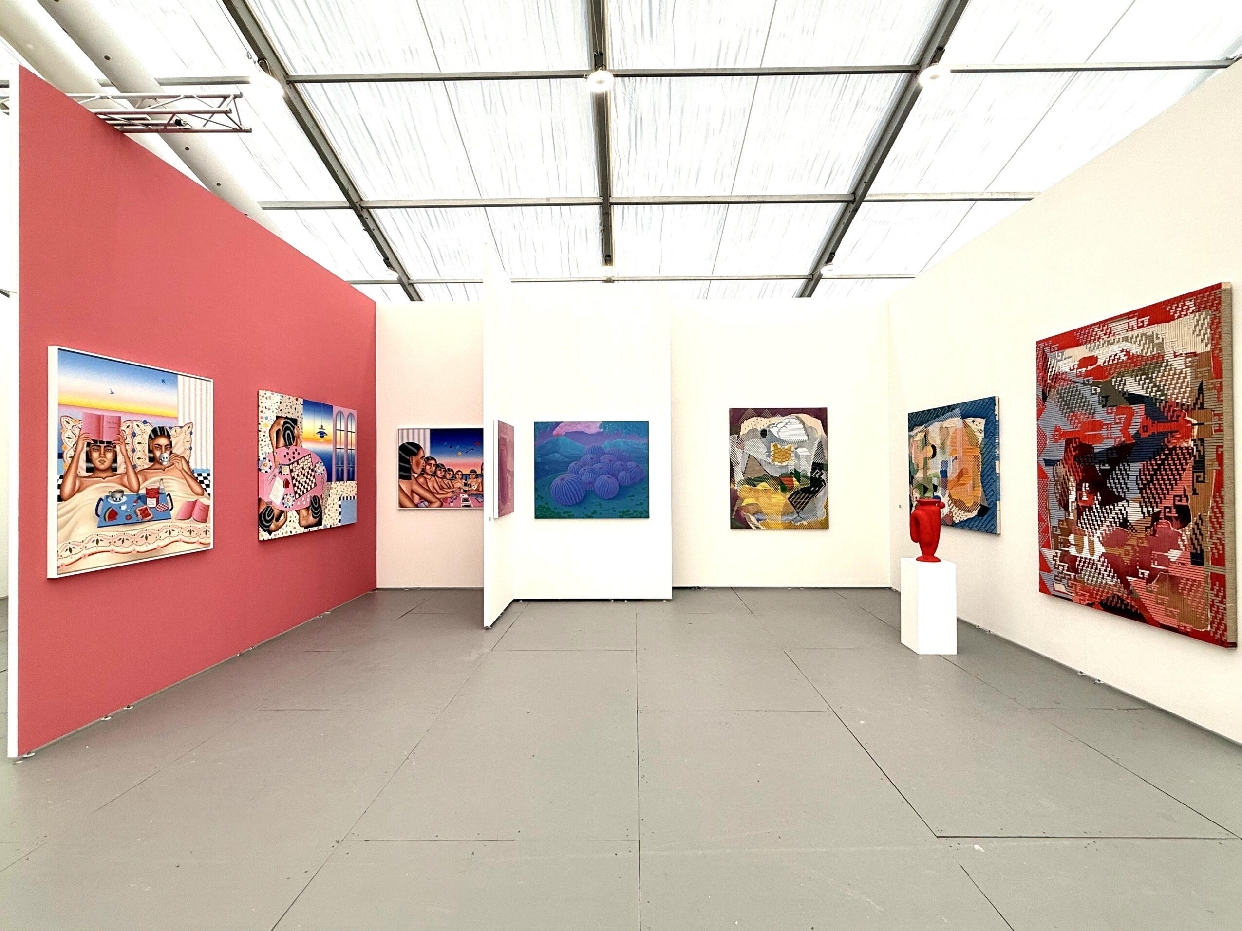 Art gallery with colorful paintings on white and red walls, white pedestal with sculpture, ceiling with grid lights.