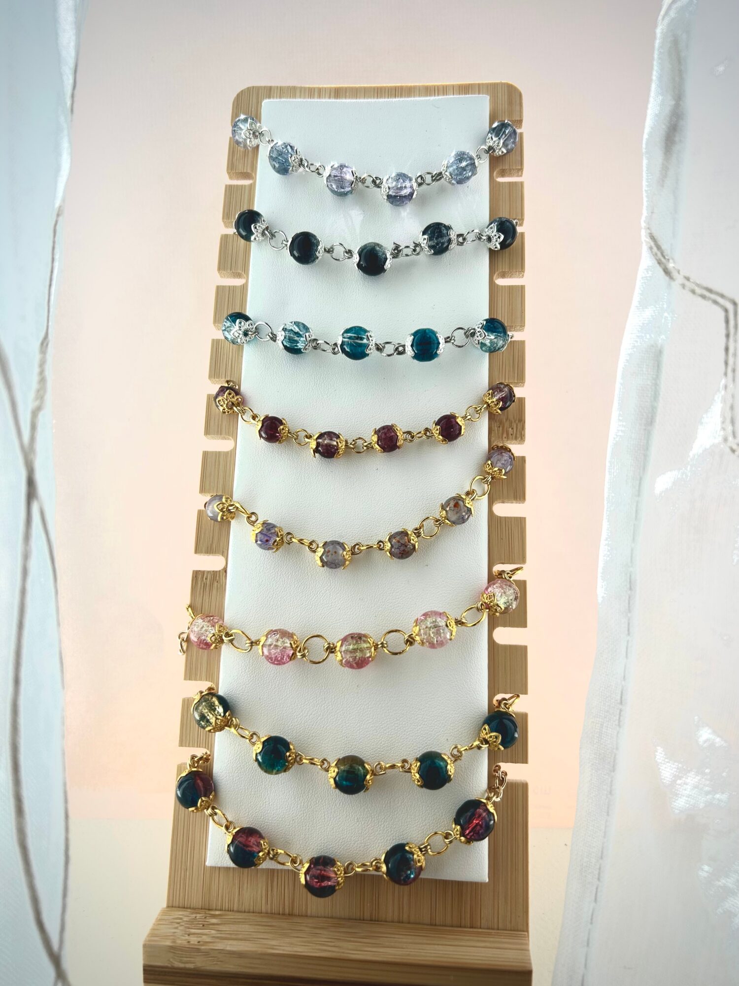 Display stand with multiple strands of colorful beaded jewelry, arranged vertically, against a light background.