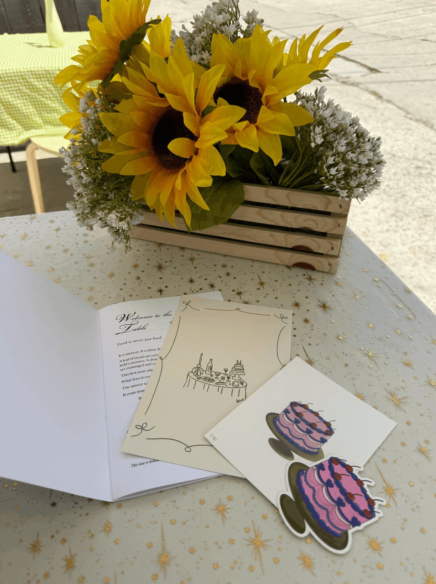 Sunflower bouquet in a wooden box on a table with cards and stickers nearby.