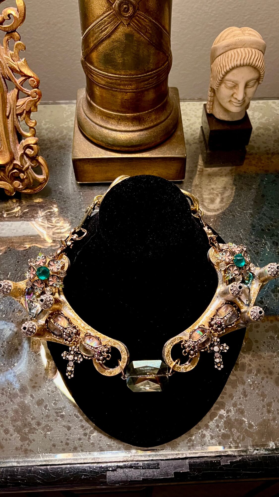 Display of jewelry with a large black bust, surrounded by decorative items including bust sculptures and ornate objects.