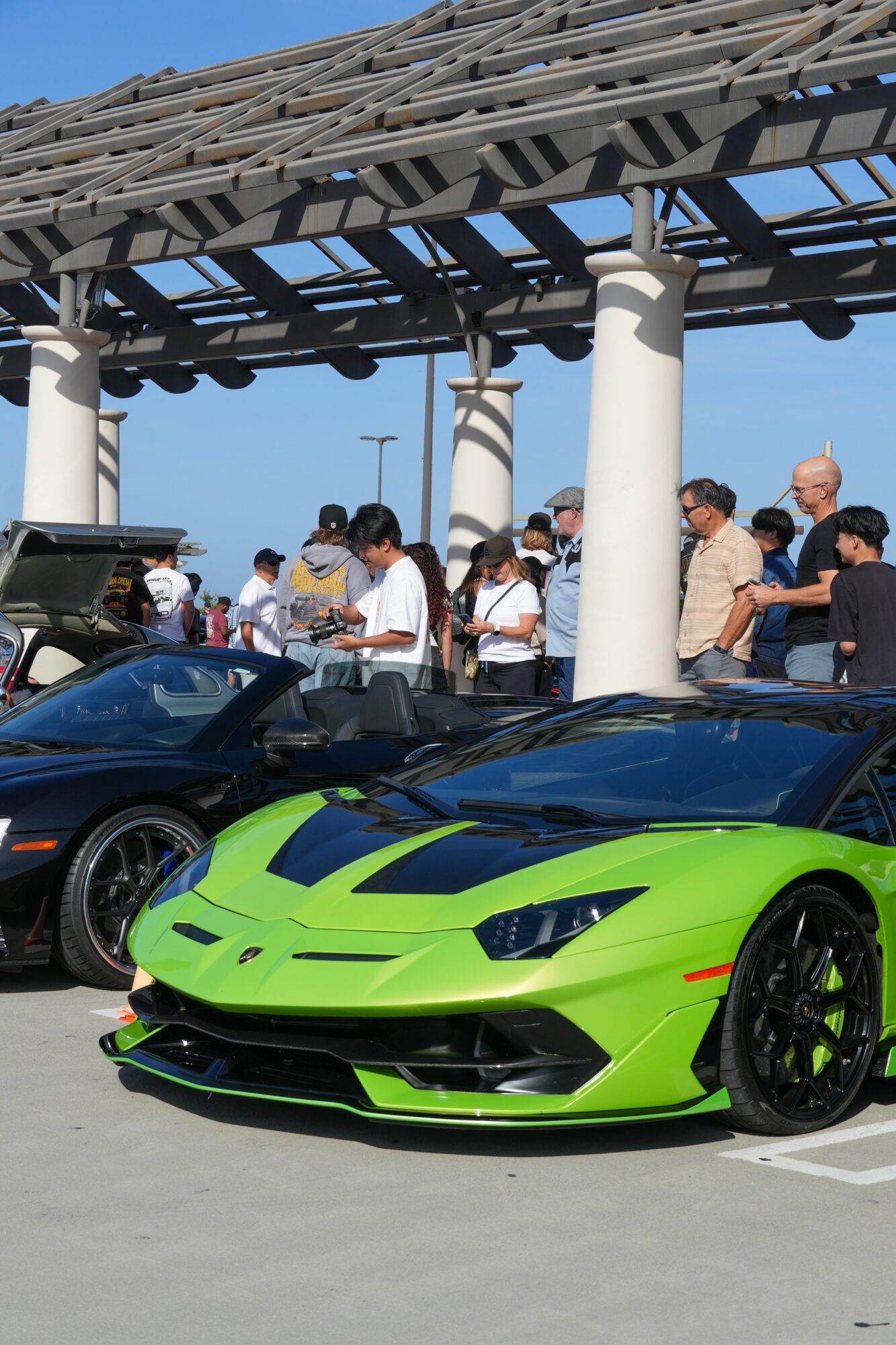 Bright green sports car parked with people and a structure overhead in the background.