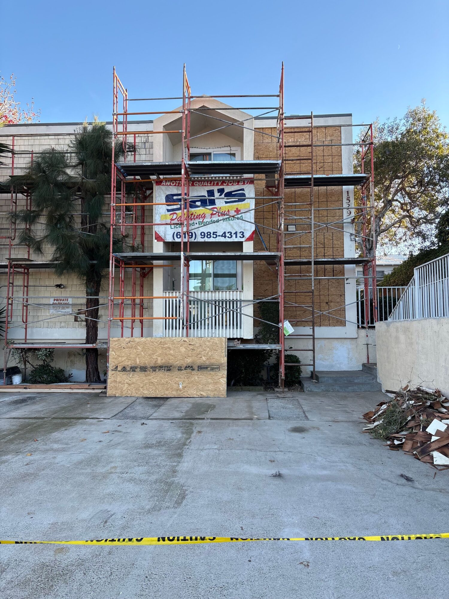 Construction site with scaffolding and building materials, a banner, and a concrete ground, viewed from the side.