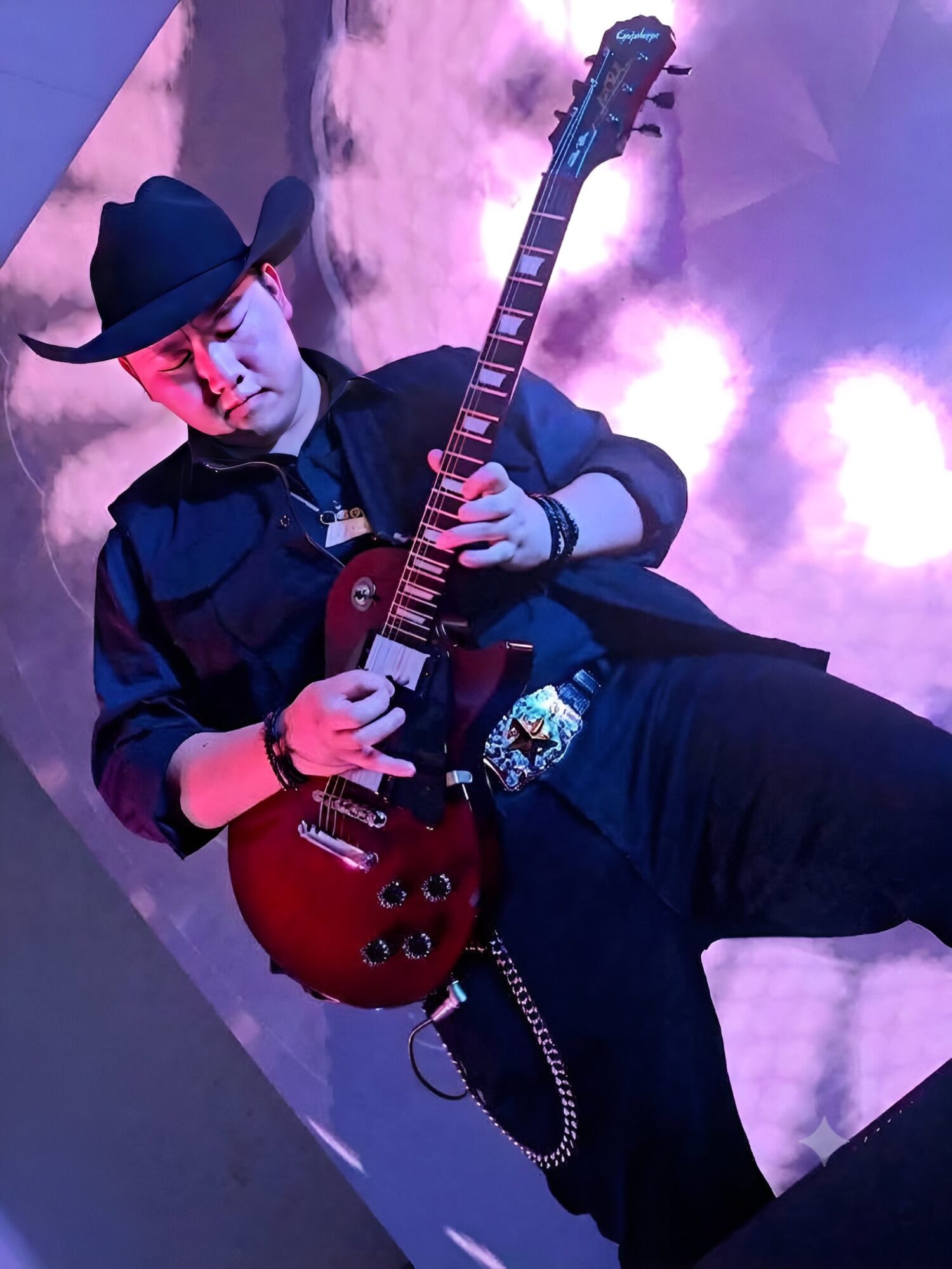 Person wearing a hat and dark clothing playing a red electric guitar on stage with purple lighting.