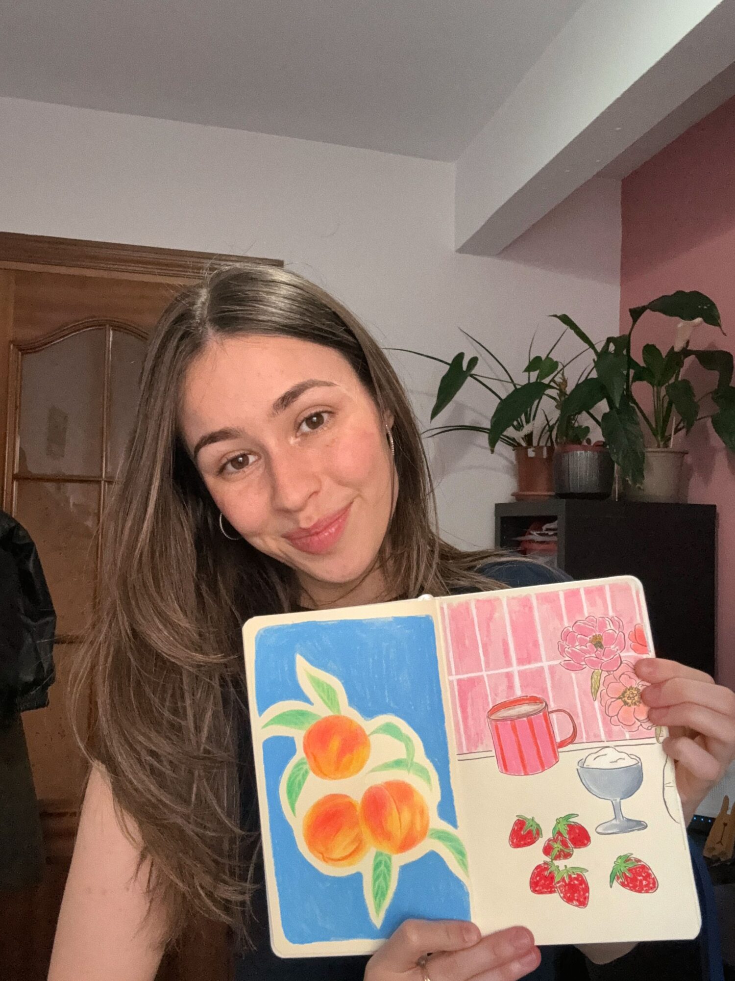 Woman holding a colorful card with strawberries, a watering can, and flowers, smiling at the camera.