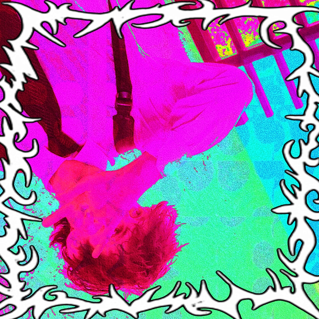 Person lying upside down on colorful floor with a decorative border, hair covering face, wearing light-colored clothing.