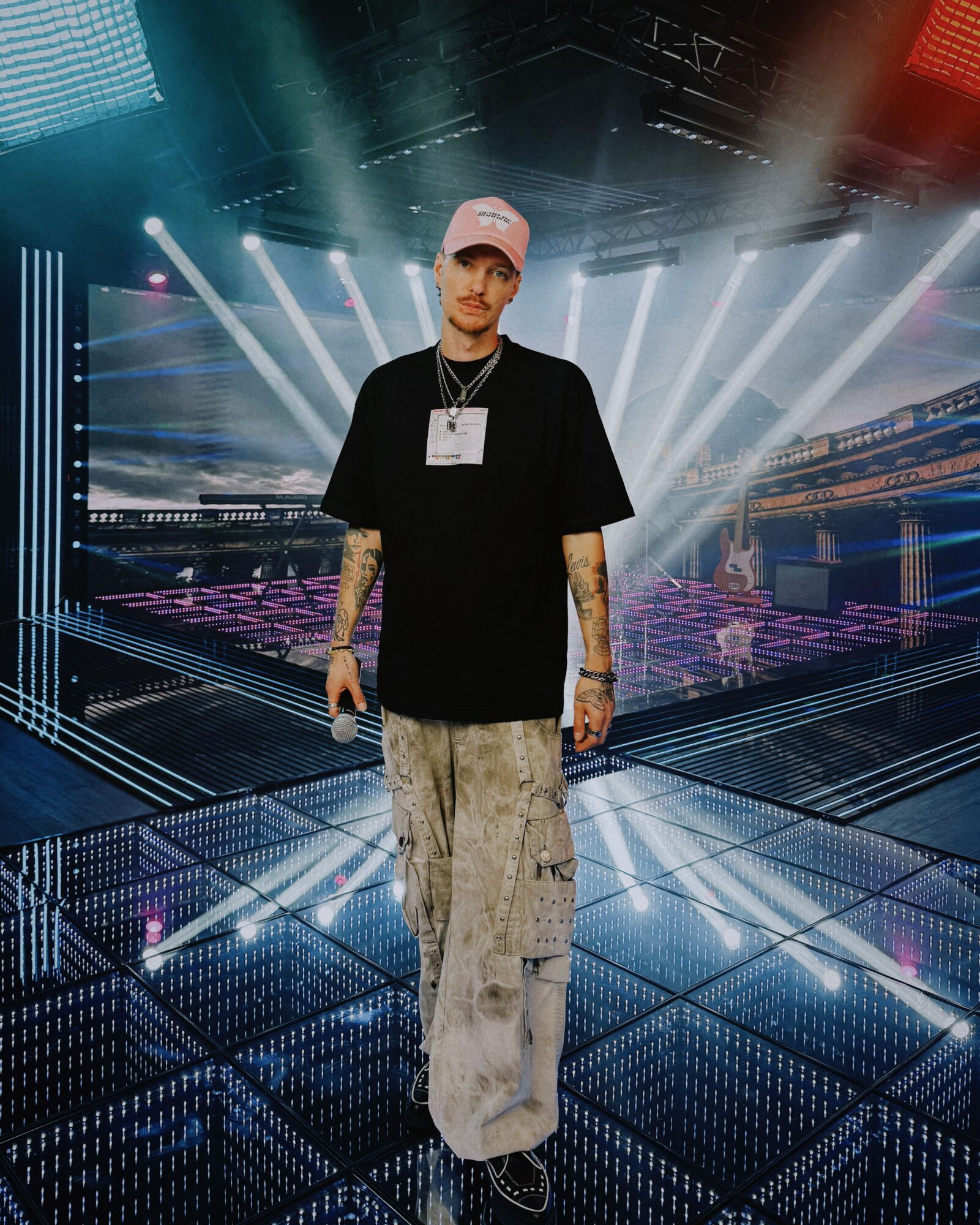 Person standing on stage with bright lights and cityscape background, wearing a black blazer and light-colored pants.