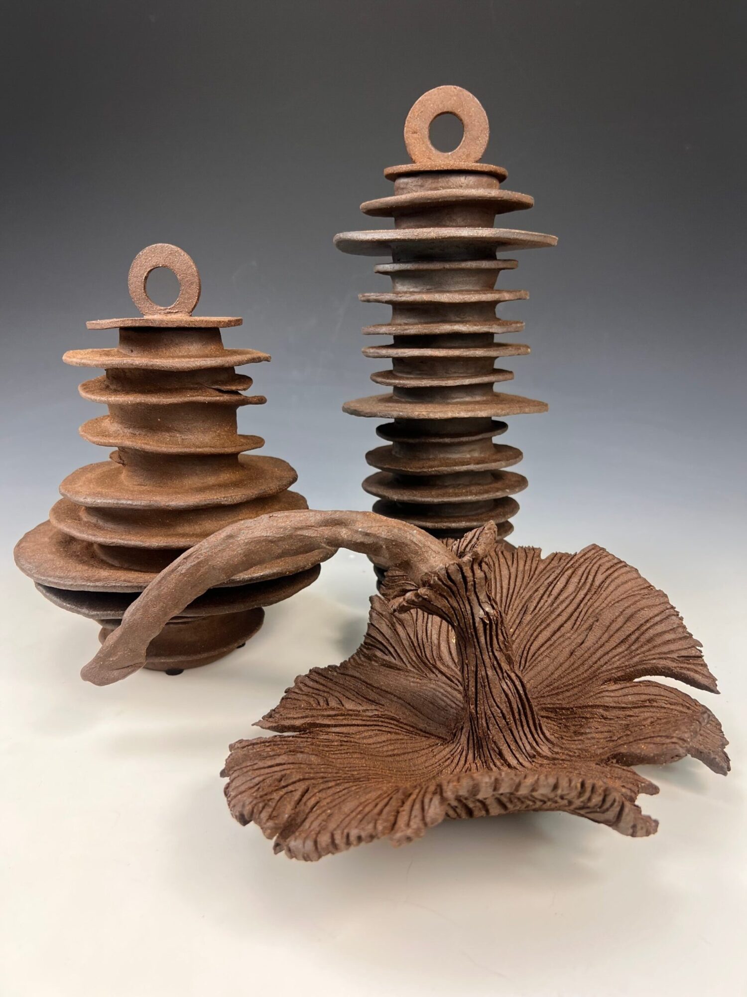 Wooden sculpture of a mushroom with a textured cap and stem, placed on a white surface.