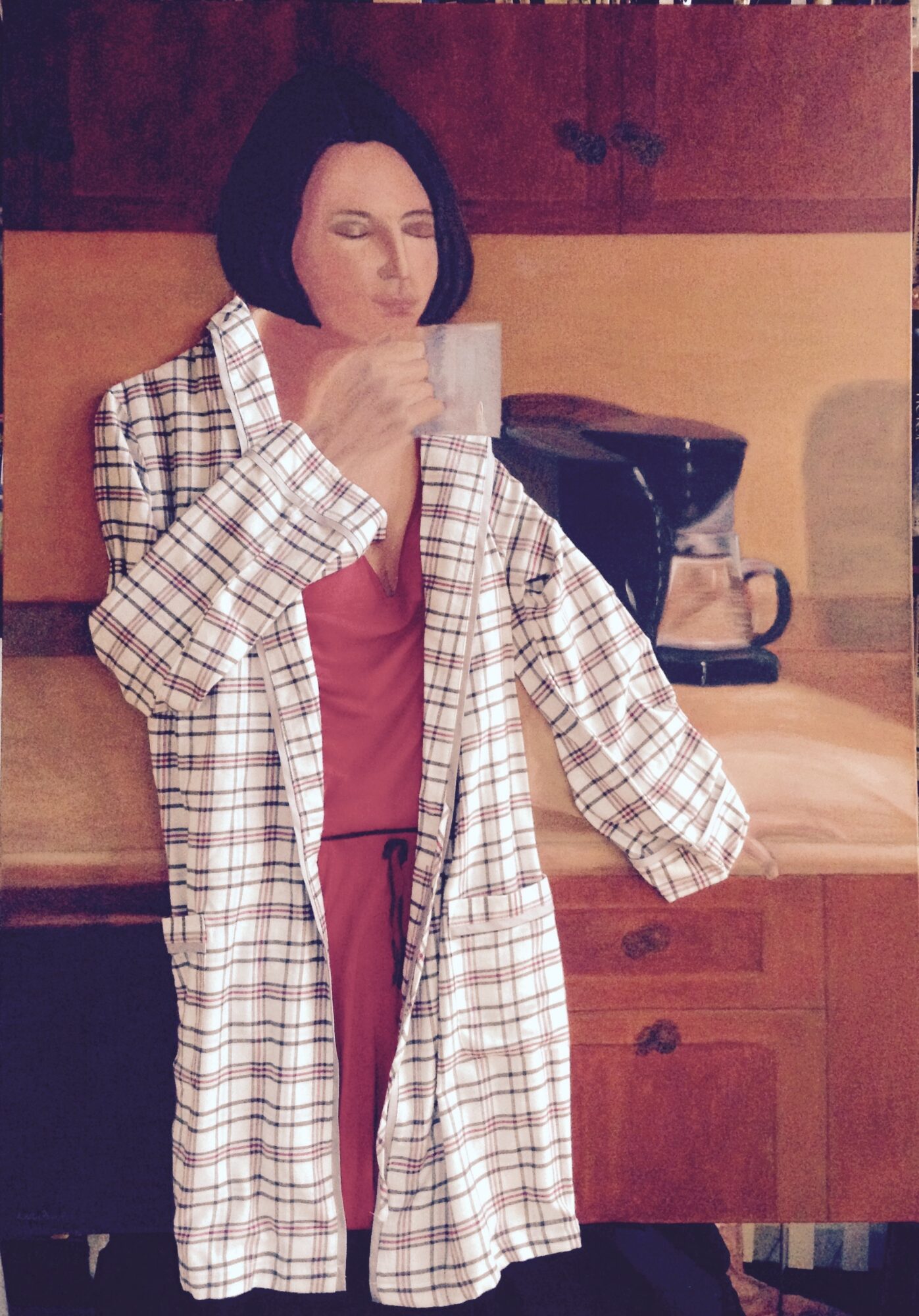 Woman with short dark hair in a checkered coat and pink dress, holding a glass, in a room with wooden furniture.