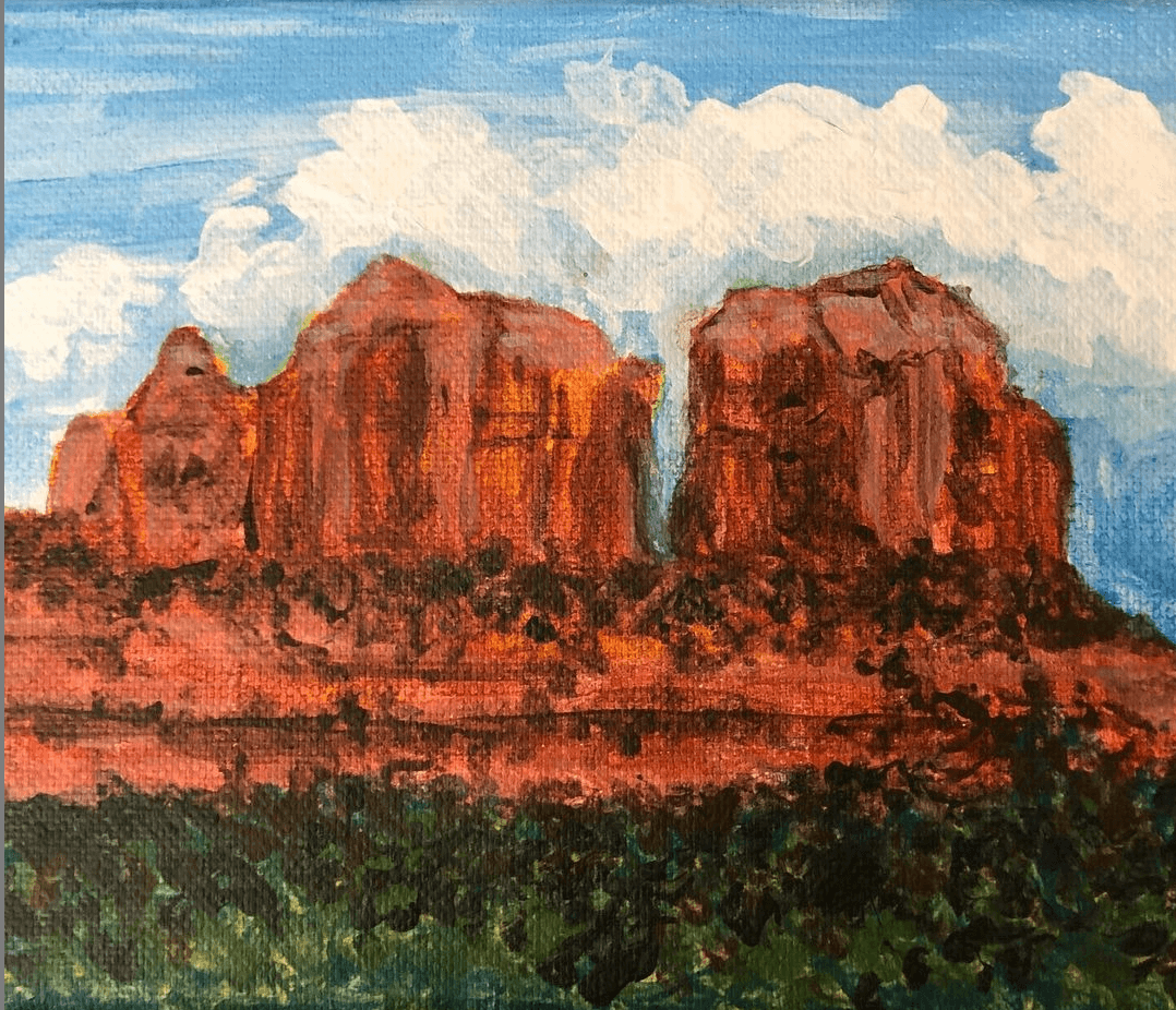 Three large red rock formations under a partly cloudy sky, with green vegetation at the base.