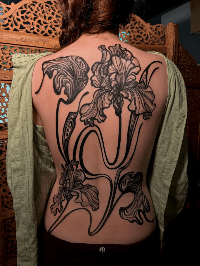 Back tattoo of large, detailed flowers with flowing lines and shading, covering the person's upper and lower back.