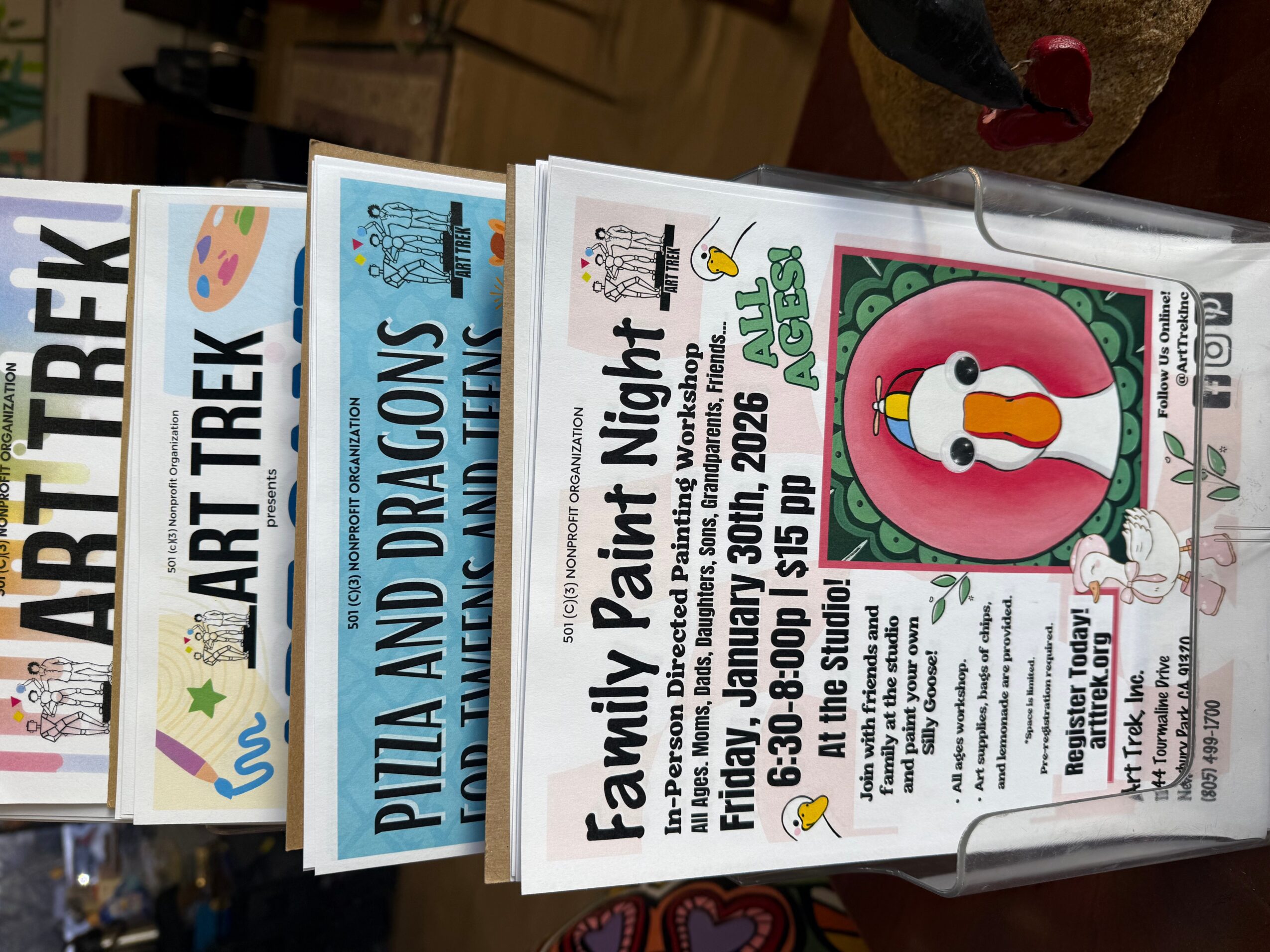 Event flyer with a penguin illustration, text about family paint night, date, time, and location details.