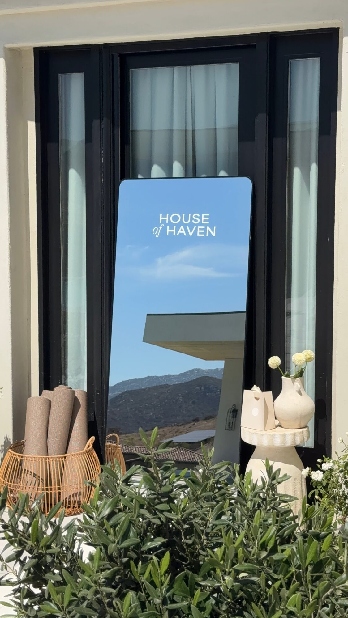 A window with a sign reading 'House of Haven' and outdoor plants and decorations in front.