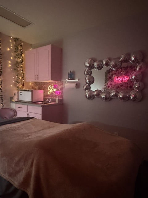 Decorative mirror with round frame, pink lights, and a pink cabinet with fairy lights in a room.