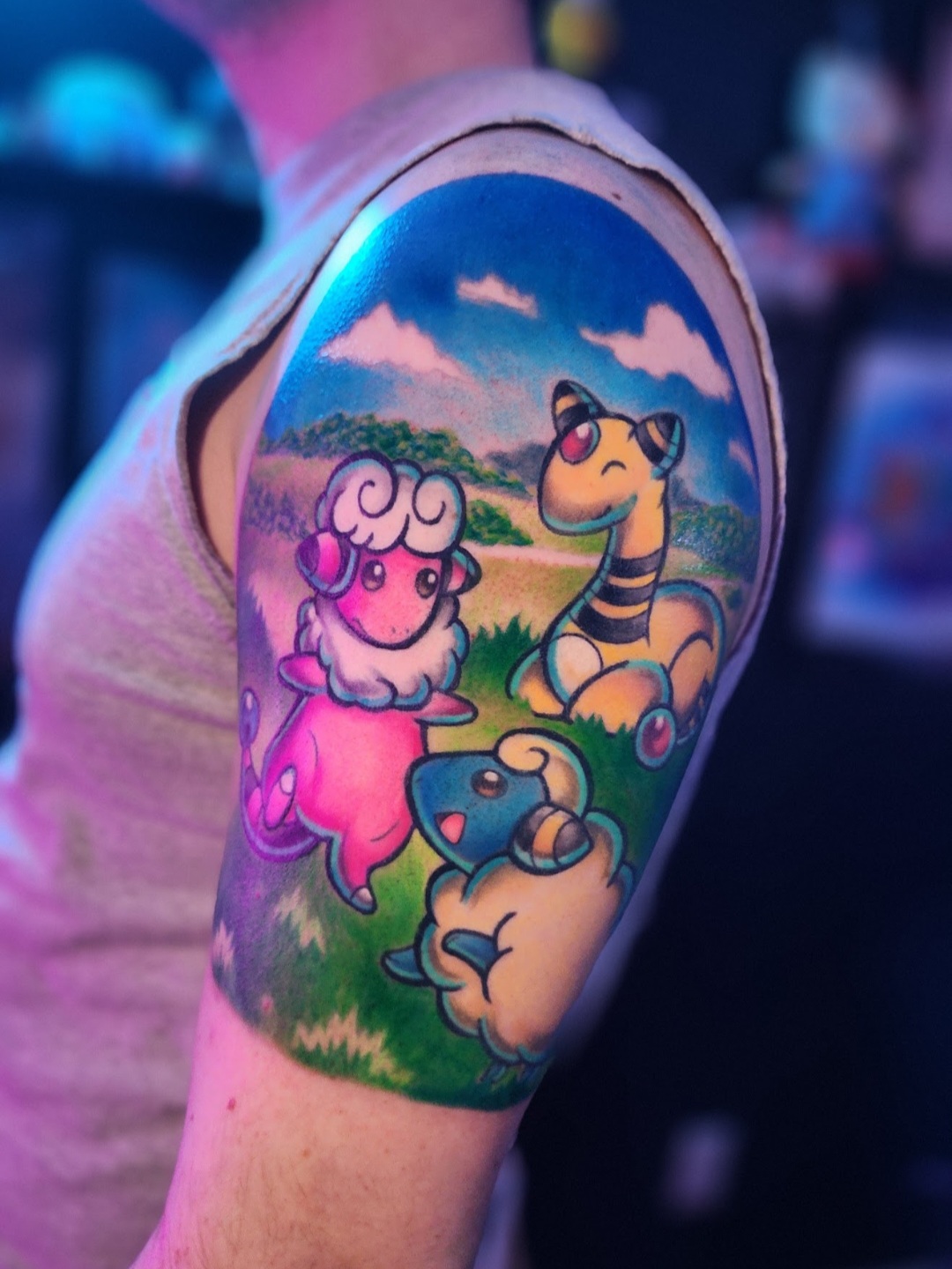 Colorful tattoo of a sheep, zebra, and dog in a grassy landscape with blue sky and clouds.