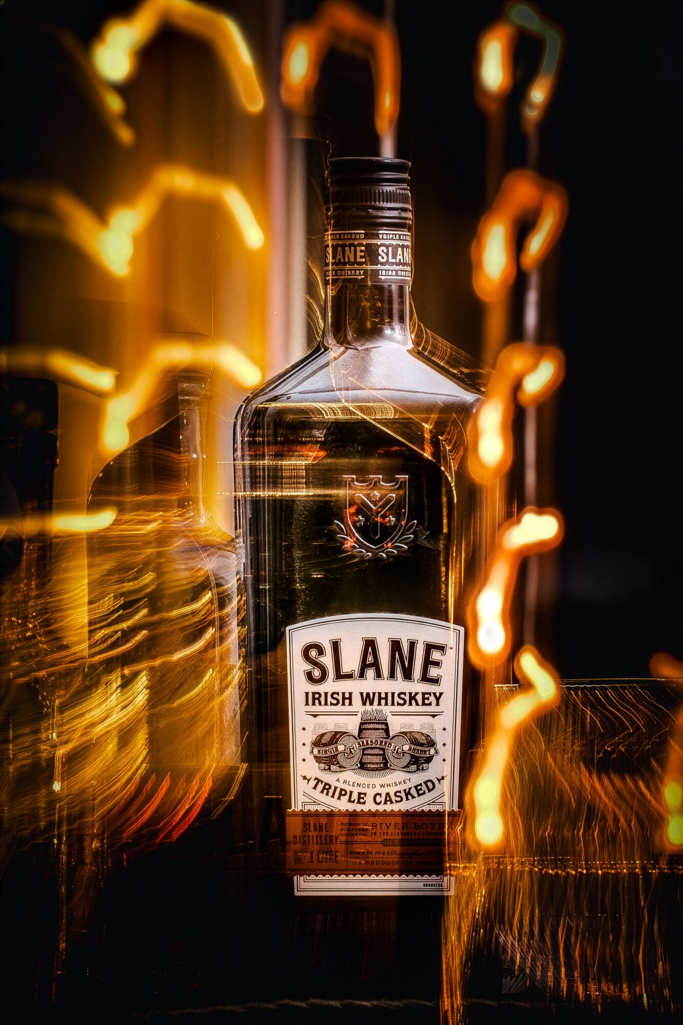 Bottle of Slane Irish Whiskey with light streaks in the background, label visible, dark setting