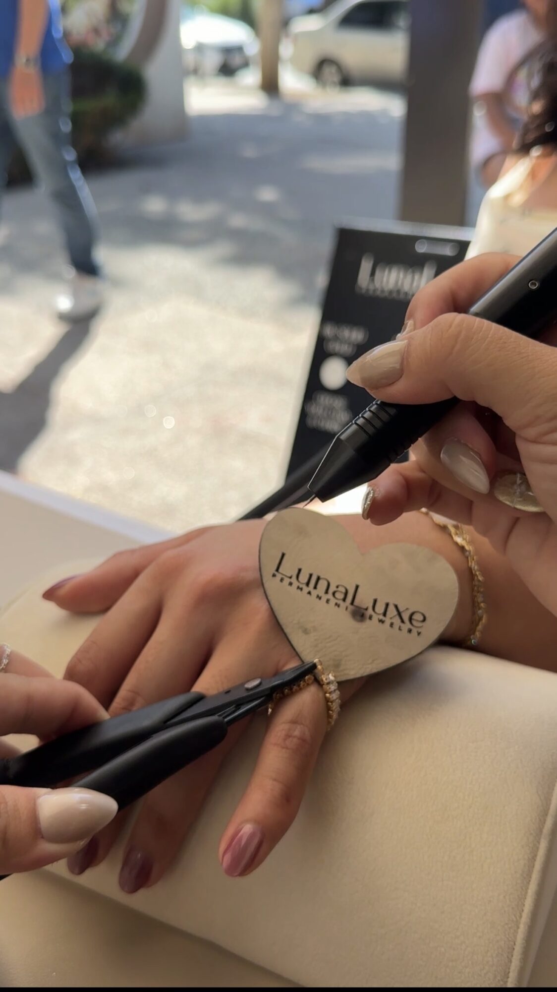 Person signing a heart-shaped object with a black marker, with hands and part of a table visible.