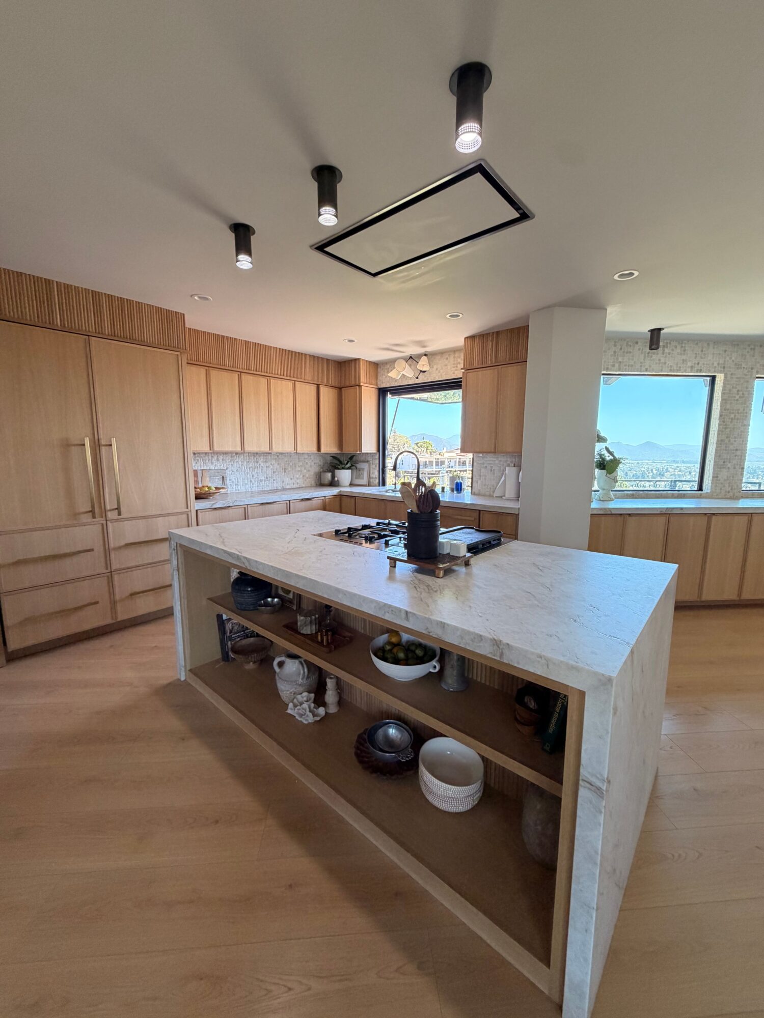 Kitchen with a white island, wooden cabinets, and a window with a view outside, viewed from below.