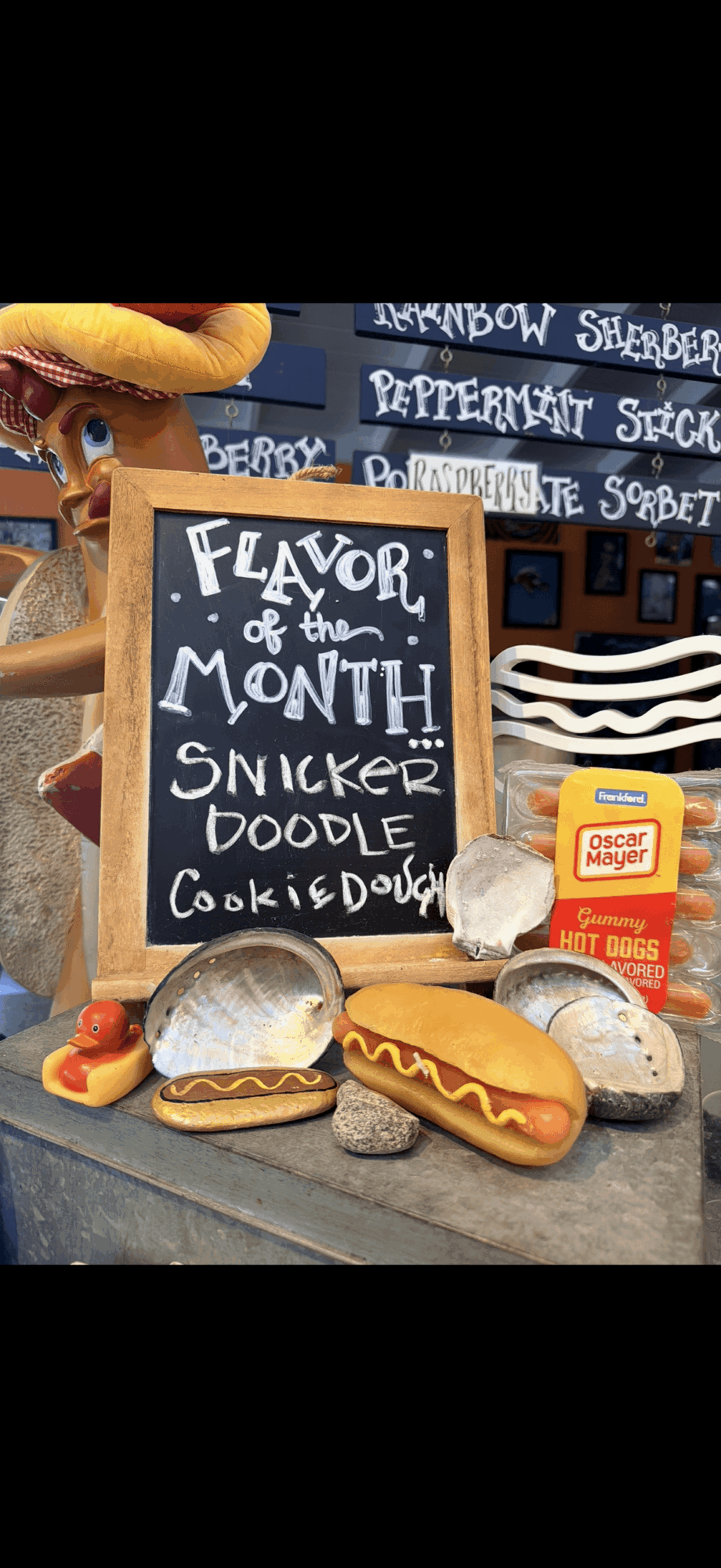 Display with a chalkboard sign, plush toys, and toy food items including hot dogs and cookies.