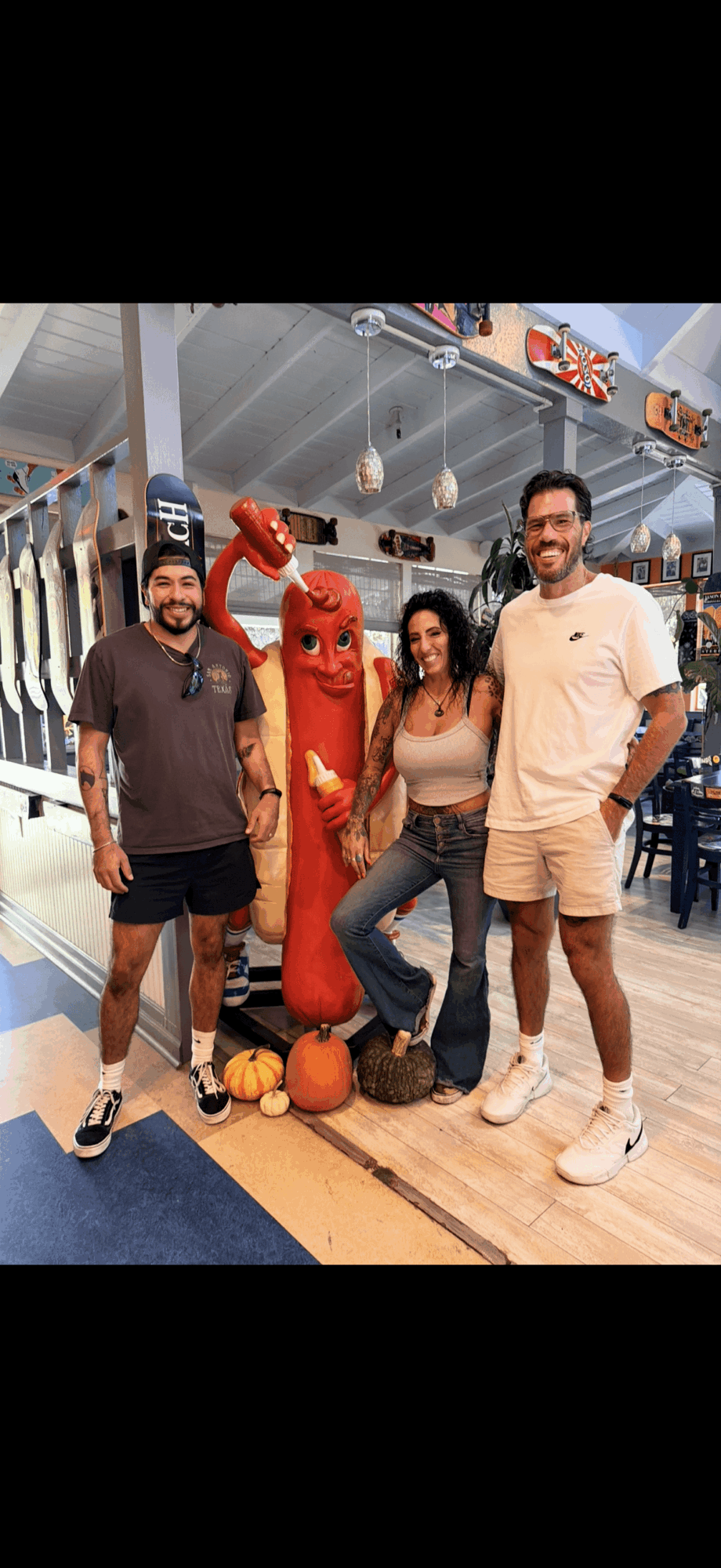 Three people and a person in a red lobster costume standing inside a store or mall, with decorations and signs visible.