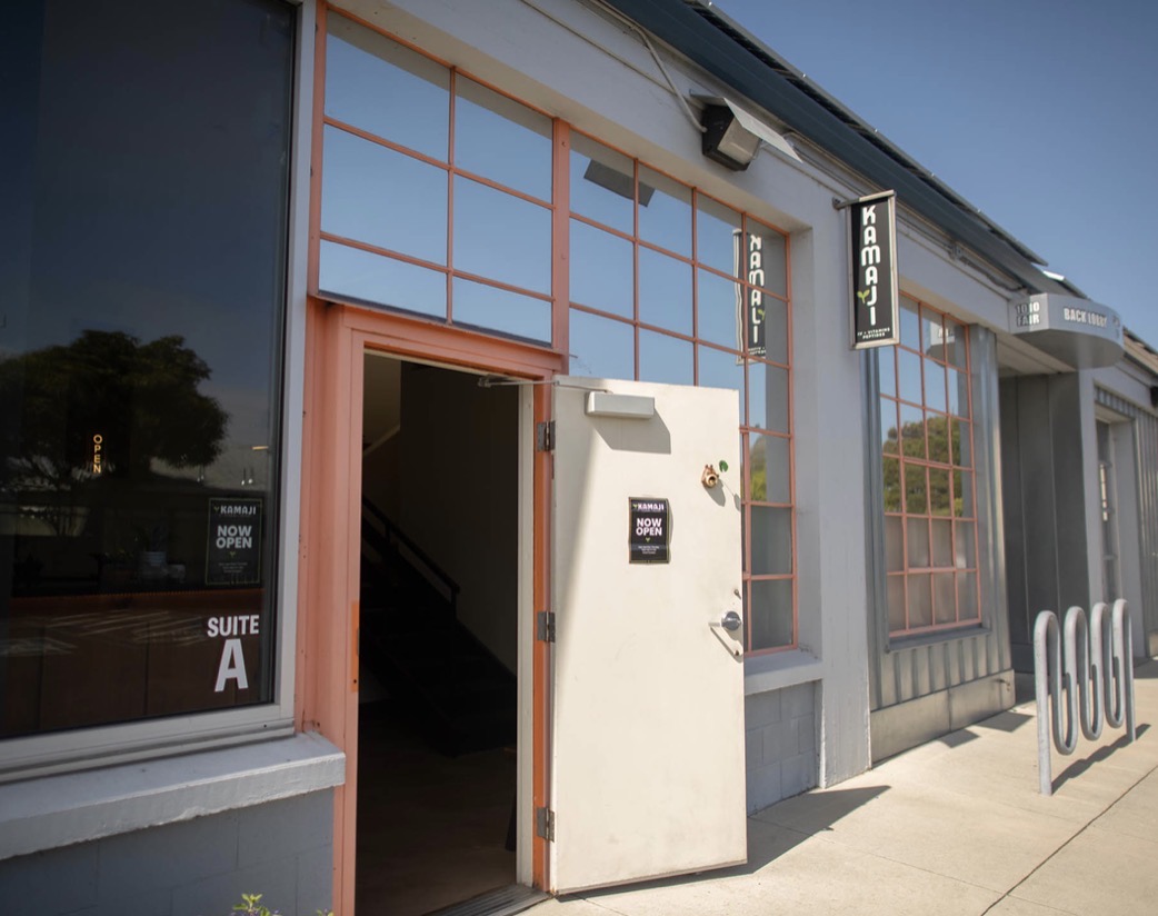 Storefront with open door, large windows, and a sign that reads 'Vegan'.