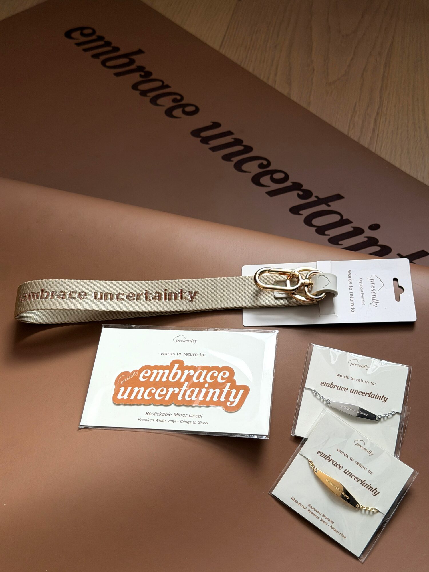 Embrace uncertainty ribbon, a card, and a small pin on a brown surface with a large printed message.