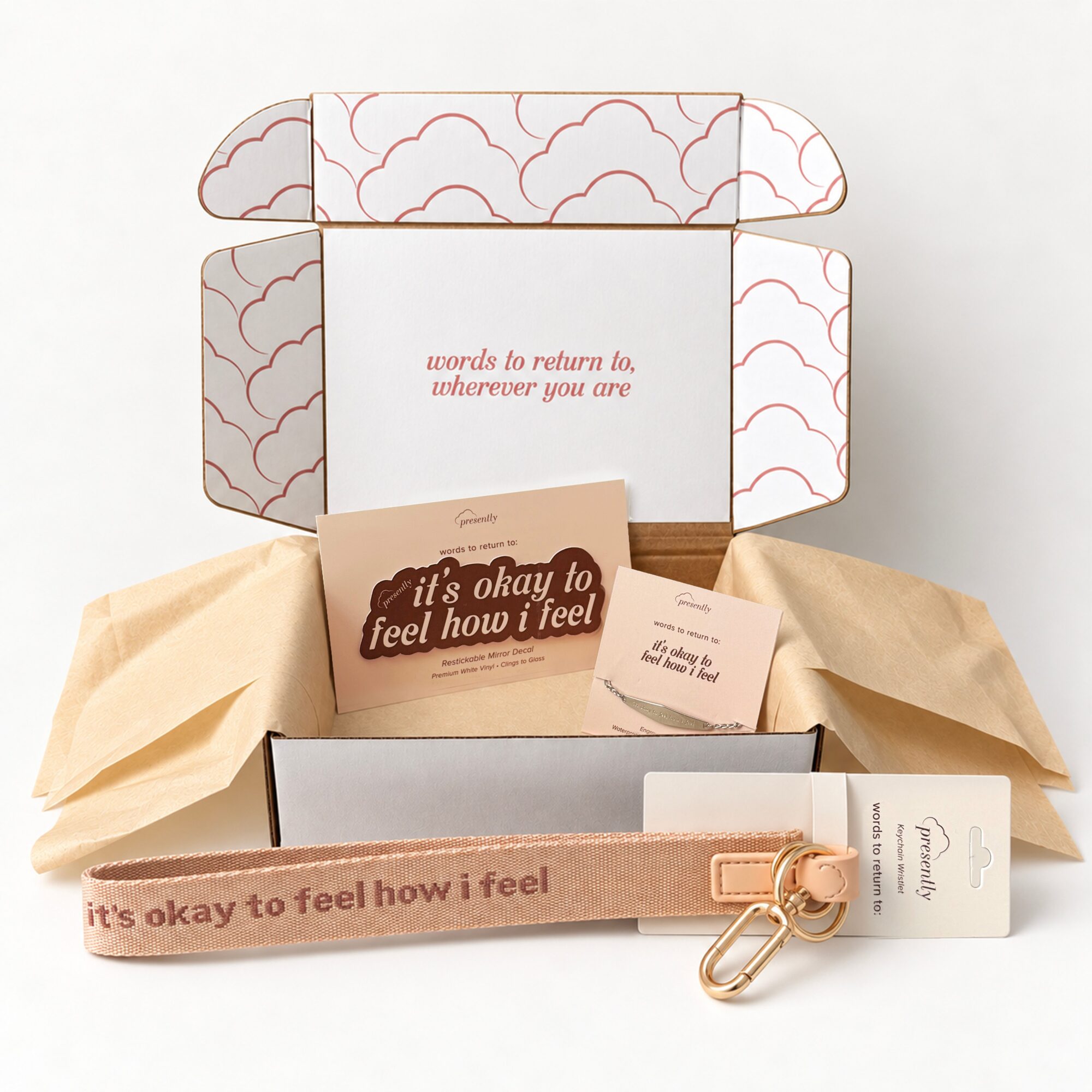 Open box with packaging items, a card, and a strap with a keyring inside. Box has cloud pattern and text. Word count: 20