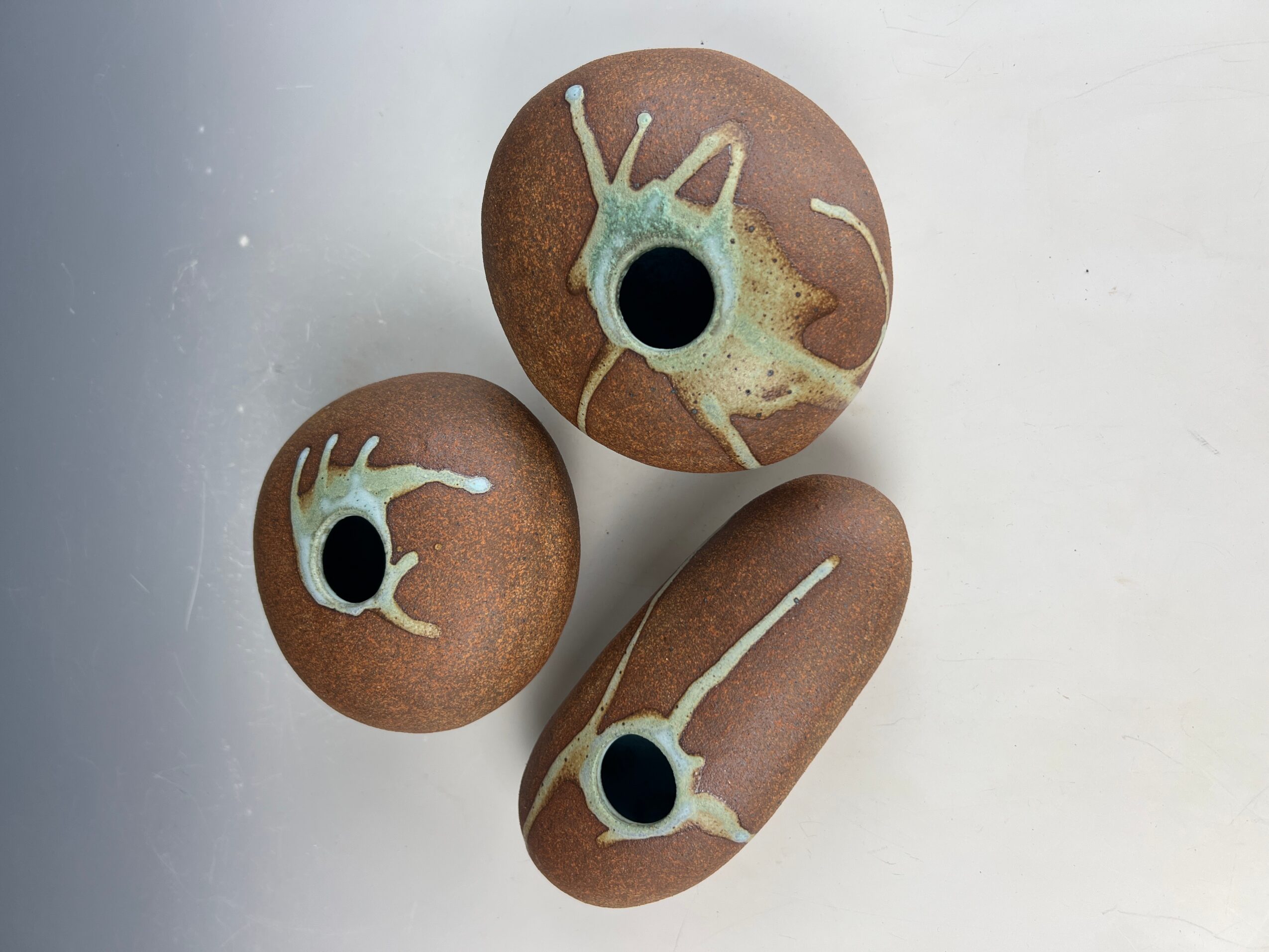 Three brown, rounded objects with black centers and white, irregular splashes on a white surface.
