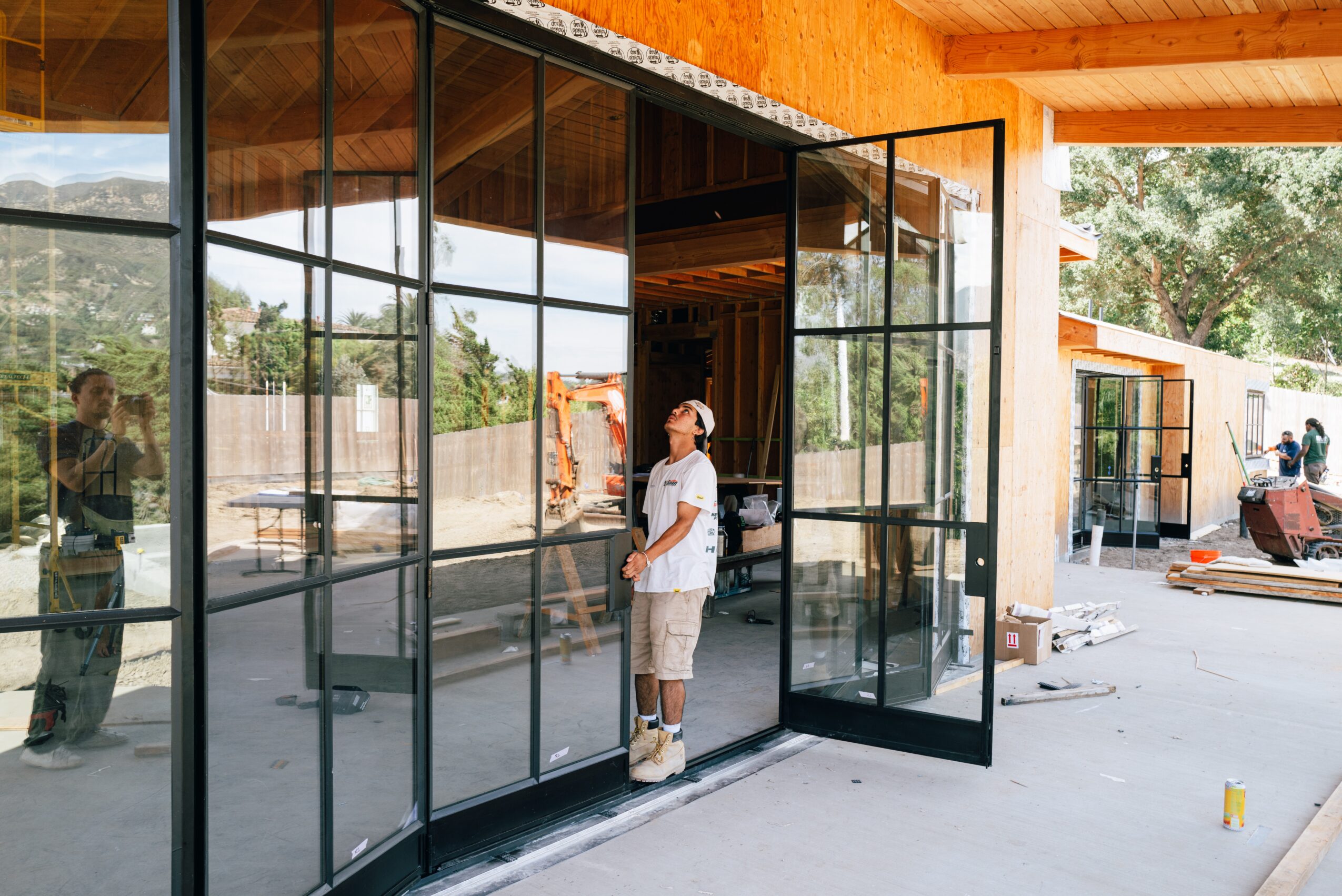 Person standing outside a glass door with a modern building in the background.