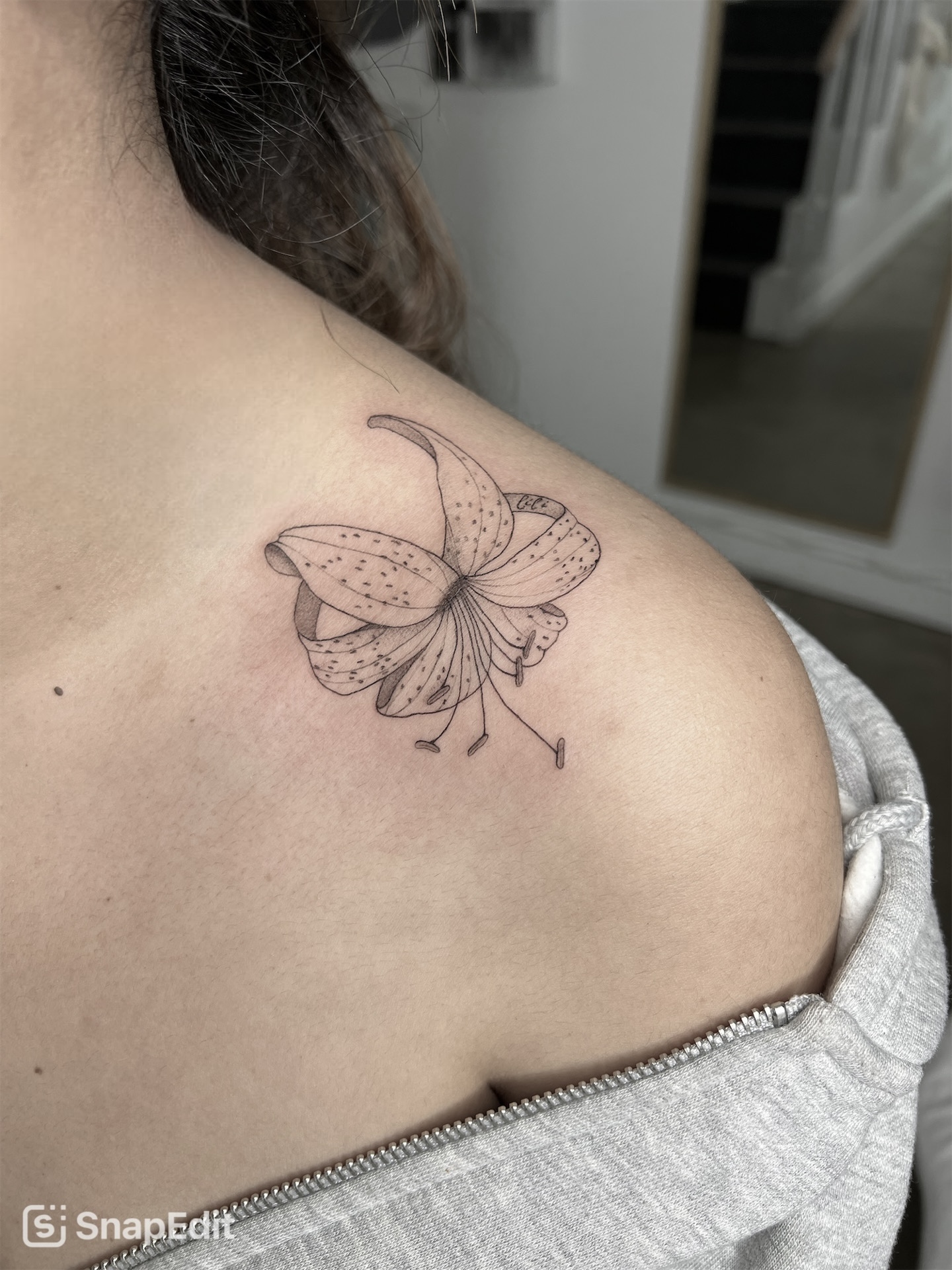 Butterfly tattoo on shoulder with detailed wings and antennae, in black ink, on light skin.