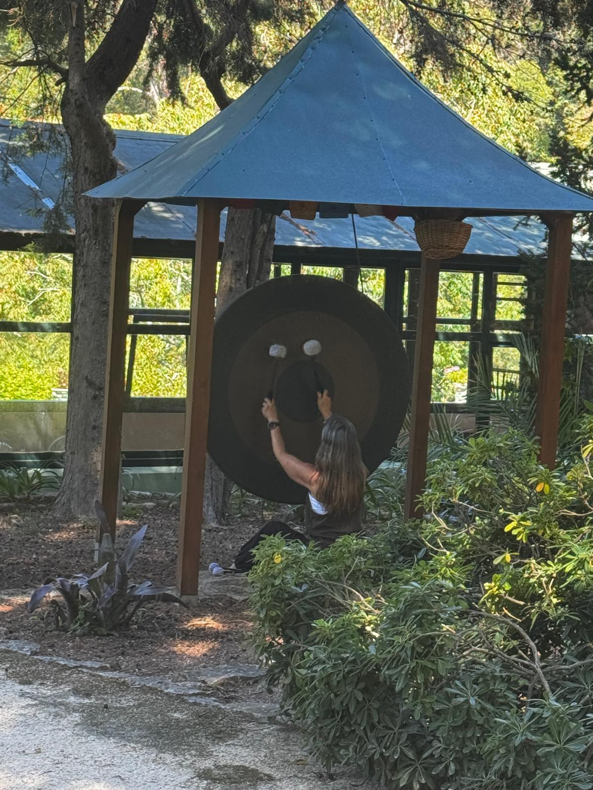 Child with long hair and a dark shirt interacts with a large circular object under a blue canopy in a park.